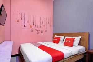a bedroom with a bed with two red pillows at OYO Life 92877 Hotel Rainbow 7296 in Semarang +21 photos