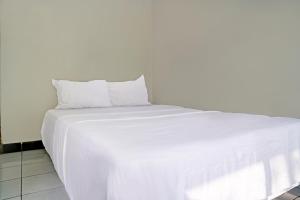 a large white bed with white sheets and pillows at Hotel O Home Stay Syariah Aom Kusman in Sukabumi +17 photos