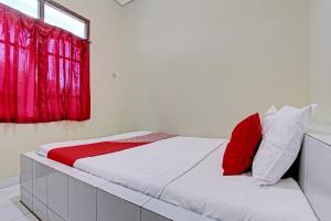 a bed in a room with a red window at OYO 92884 Agustha Homestay in Yogyakarta