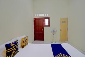 a room with a bed and a door with a fan at Hotel O Sunyoto Homestay Syariah in Mojokerto