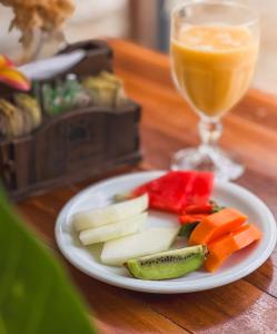 a plate of fruit and vegetables with a glass of juice at Pousada Porto Verano in Porto De Galinhas