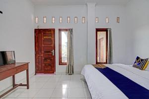 a bedroom with a bed and a tv and a window at Hotel O Meranti HomestayNearJembatan Siak in Pekanbaru