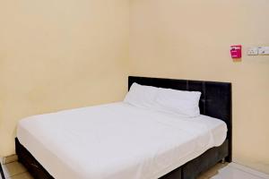 - un lit blanc avec une tête de lit noire dans la chambre dans l'établissement Hotel O Toyo Homestay Syariah, à Nagoya