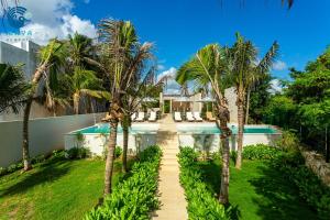 a path leading to a swimming pool with palm trees at Luxurious penthouse by the beach in Akumal