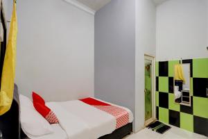 Cette petite chambre comprend un lit avec des oreillers rouges. dans l'établissement Hotel O Backpaker Seraya, à Nagoya