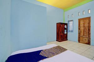 a bedroom with a bed with blue walls and a door at OYO Life 93037 Nova Jaya Homestay Syariah in Lamongan +20 photos