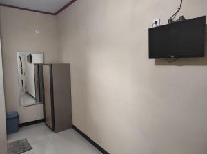 EnrekangHotel O Wisma Astukara Syariah Near Sejahtera Department Store Pinrang的一间设有冰箱和墙上电视的客房
