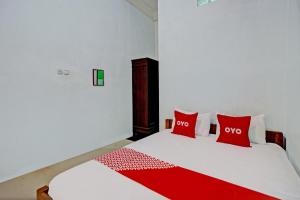 - une chambre avec un lit blanc et 2 oreillers rouges dans l'établissement OYO Life 93036 Eddy Homestay Syariah, à Lamongan