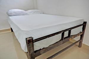 - un petit lit avec des draps blancs et des oreillers dans l'établissement OYO Life 92919 Kost Wijaya Kusuma Lake Syariah, à Madiun