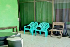 3 chaises et une table dans une pièce aux murs verts dans l'établissement OYO Life 92919 Kost Wijaya Kusuma Lake Syariah, à Madiun