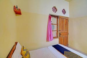 a bedroom with a bed and a window and a door at OYO Life 92954 Shanti Kost in Singaraja