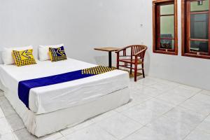 a bedroom with a bed and a table and a chair at OYO Life 93075 Nova Jaya 2 Homestay Syariah in Lamongan