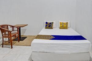a bed in a room with a chair and a table at OYO Life 93075 Nova Jaya 2 Homestay Syariah in Lamongan +18 photos