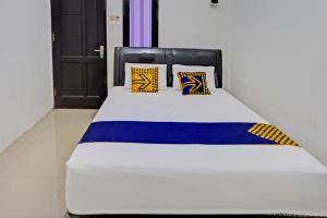a white bed with yellow and blue pillows on it at OYO Life 93075 Nova Jaya 2 Homestay Syariah in Lamongan