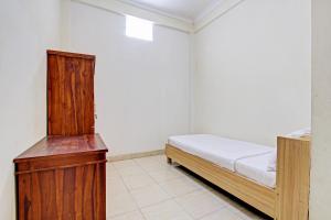 a bedroom with a bed and a wooden cabinet at OYO Life 92663 Karmel 6 in Purwokerto