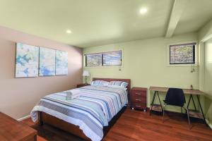 a bedroom with a bed and a desk and windows at Red Gum Beach Retreat in Cowes