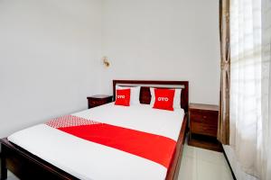 a bedroom with a bed with two red pillows at OYO Life 93083 Nova Jaya 3 Homestay Syariah in Lamongan