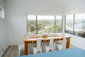 a dining room table with white chairs and a large window at Port Campbell Coastal Unit 3 in Port Campbell