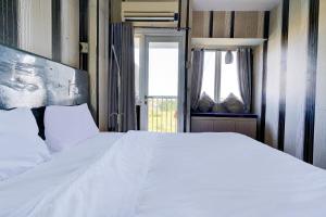 カラワンにあるOYO Life 92874 Apartement Grand Sentraland Karawang By Red Dragonの白いベッドと窓のある寝室