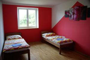 two beds in a room with red walls and a window at Penzion u Tomčalů in Terezín