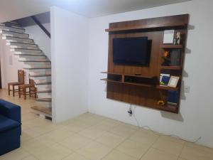 a living room with a tv and a staircase at Casa de férias in Arroio do Sal