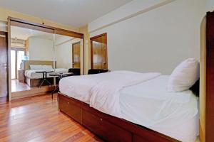 een slaapkamer met een groot wit bed en een spiegel bij OYO Life 92949 Apartemen Gateway Cicadas By Qq Rent in Bandung