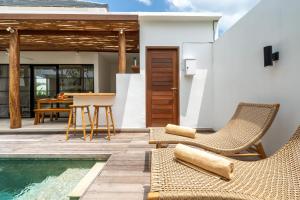 a villa with a pool and chairs and a table at Villa Camille - Private 1BR Oasis with Pool in Nyanyi Beach in Tanah Lot
