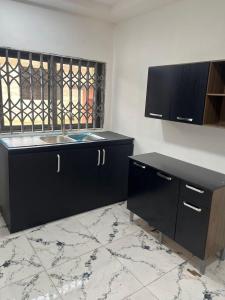 a kitchen with black cabinets and a sink and a window at Amazing Rental Property in Adenta ,Accra in Accra