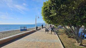 people sitting at tables on a sidewalk near the beach at Apartamento Marion in Cala del Moral