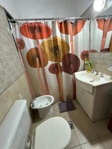 a bathroom with a toilet and a shower curtain with umbrellas at Departamento con Balcón y Asador in Río Cuarto