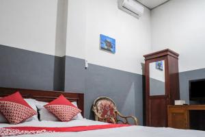a bedroom with a bed with red pillows and a television at OYO 93117 Penginapan Tiga Dara in Jayapura +19 photos