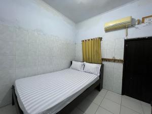 a small bed in a room with a yellow curtain at Hotel O Kost Maharaja Near Maros in Makassar