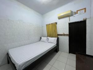 a small bed in a room with a window at Hotel O Kost Maharaja Near Maros in Makassar