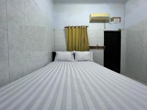 a large bed in a room with a yellow curtain at Hotel O Kost Maharaja Near Maros in Makassar