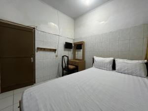 a bedroom with a white bed and a chair at Hotel O Kost Maharaja Near Maros in Makassar +36 photos