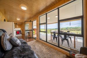 a living room with a table and a large window at Strathvale River Cottage - Winton Holiday Home in Winton