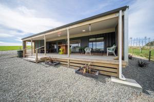 a house with a large deck with plants in front of it at Strathvale River Cottage - Winton Holiday Home in Winton