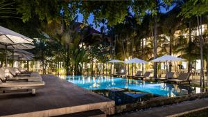 a swimming pool with lounge chairs and umbrellas at Pavillon d'Orient Boutique Hotel in Siem Reap