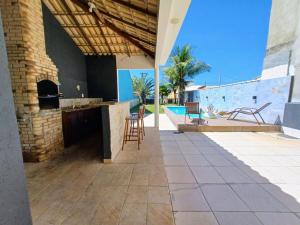 a patio of a house with chairs and a pool at Casa com 3 suítes em Cabo Frio com piscina há poucos passos do Mar! in Cabo Frio