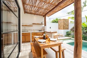an open kitchen and dining area with a wooden table at Villa Camille - Private 1BR Oasis with Pool in Nyanyi Beach in Tanah Lot