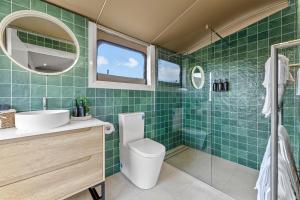 a green tiled bathroom with a toilet and a sink at Jara II in Berremangra
