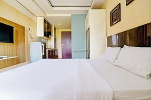 a large white bed in a room with a refrigerator at OYO Life 93170 Apartement Gateway Cicadas By Mr Pro in Bandung