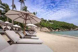 a row of chairs and umbrellas on a beach at Banyan Tree Samui in Lamai