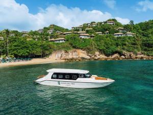 a white boat in the water near a beach at Banyan Tree Samui in Lamai