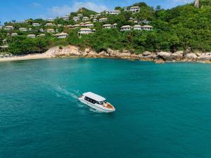 a boat in the water next to a beach at Banyan Tree Samui in Lamai