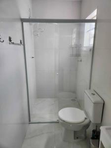 un bagno bianco con doccia e WC di Apartamento - 4 pé na areia proximo a lagoa e rio a Passo de Torres