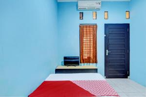 a blue room with a bed and a window and a door at OYO 93209 Guest House Cemara 3 in Tegal