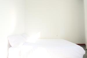 BagamにあるHotel O Homestay OrangeNearNagoya Hill Shopping Mallの白いベッド(白いシーツ、枕付)