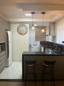 a kitchen with two bar stools and a clock on the wall at Apartamento Maitinga aconchegante in Bertioga +13 photos