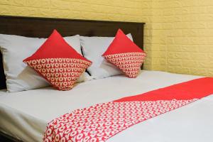a bed with two red pillows on top of it at OYO 93333 Rama Home Stay in Jayapura